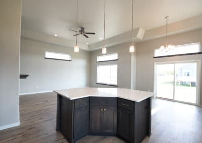 View of kitchen island and open dining area with vaulted ceiling