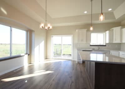 View of kitchen with white cupboards, island, and view out of the back sliding glass door
