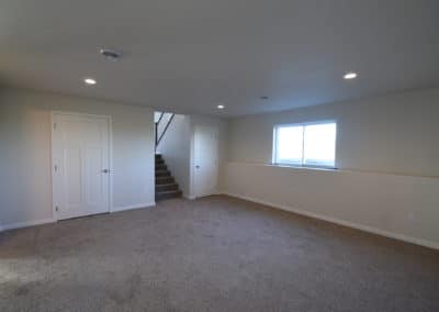 View of large carpeted living area with stairs to front door