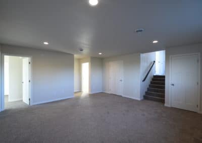 View of large carpeted living area with stairs to front door